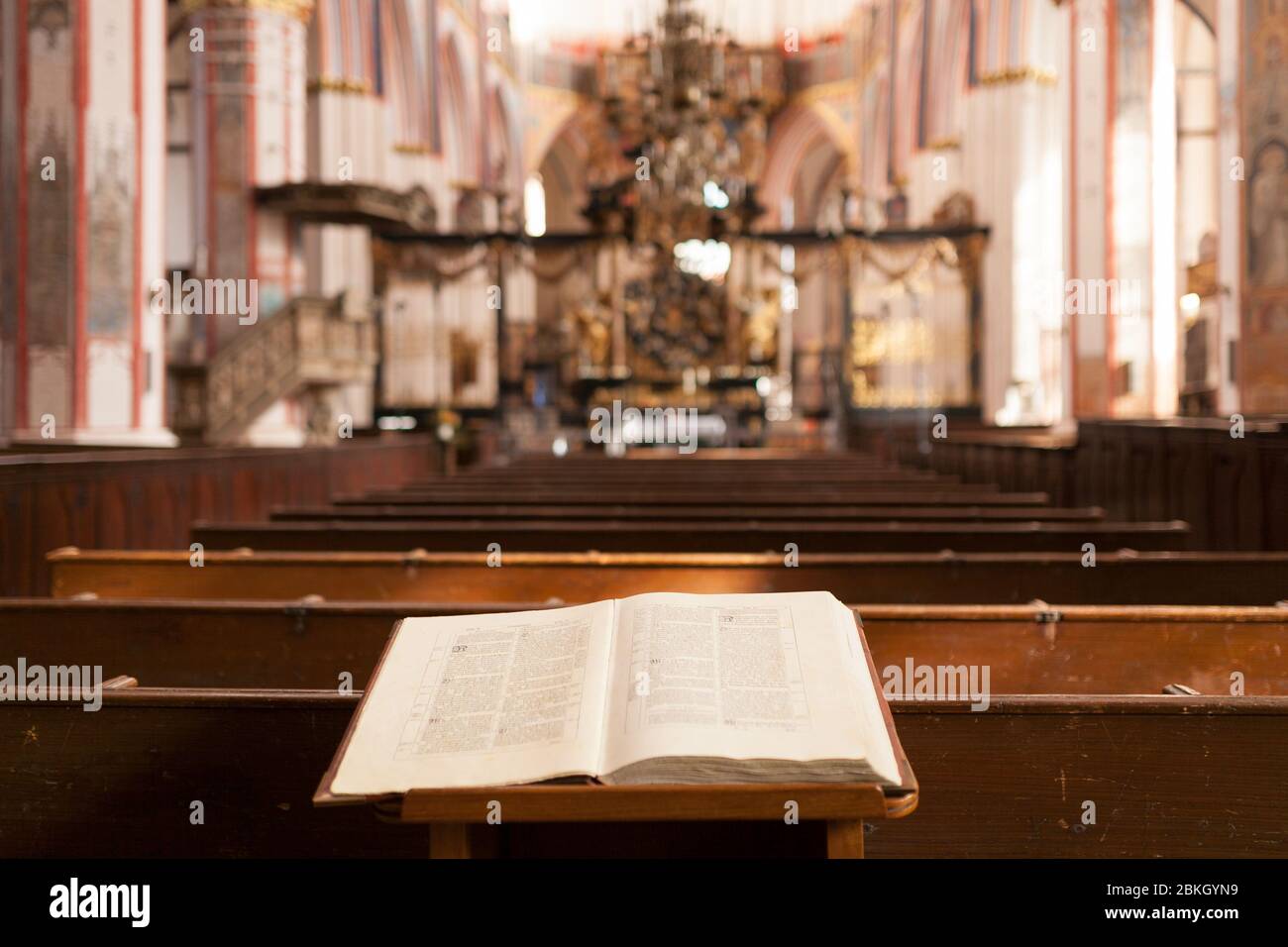 Bibel um Bänke vor dem Hintergrund des Altars in der katholischen Kirche Stockfoto