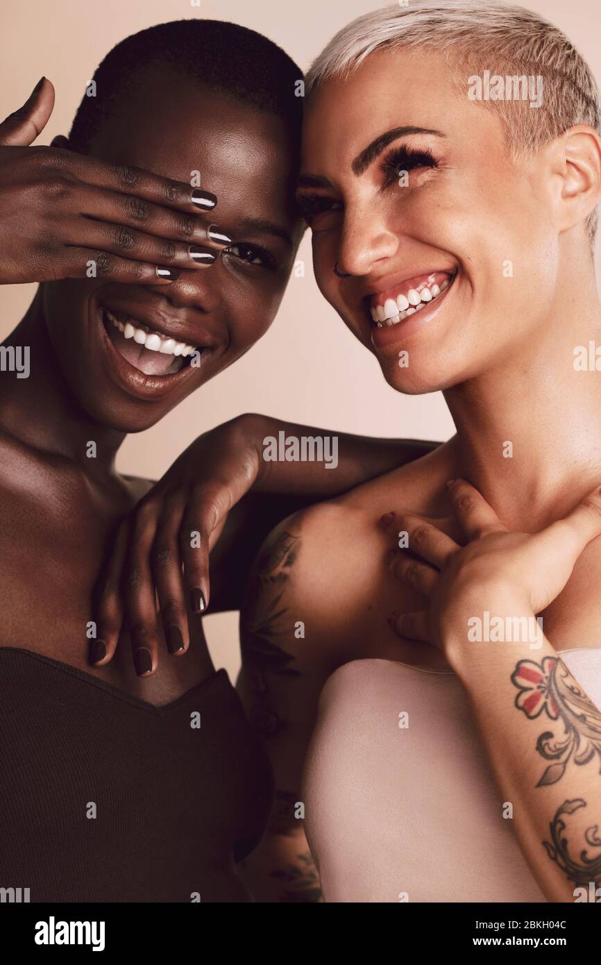Zwei Frauen stehen zusammen und haben Spaß. Multi-ethnische weibliche Modelle mit kurzen Frisur lächelnd im Studio. Stockfoto