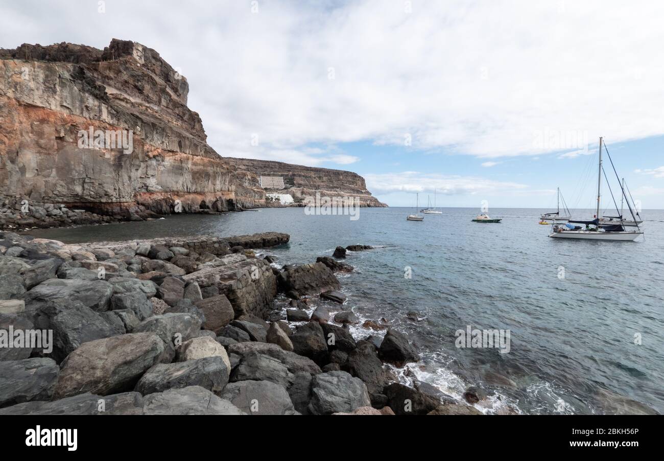 Yachten vor der felsigen Südküste von Gran Canaria, die Zuflucht in der Schutz der Klippen in der Bucht bei Puerto de Mogan. Stockfoto