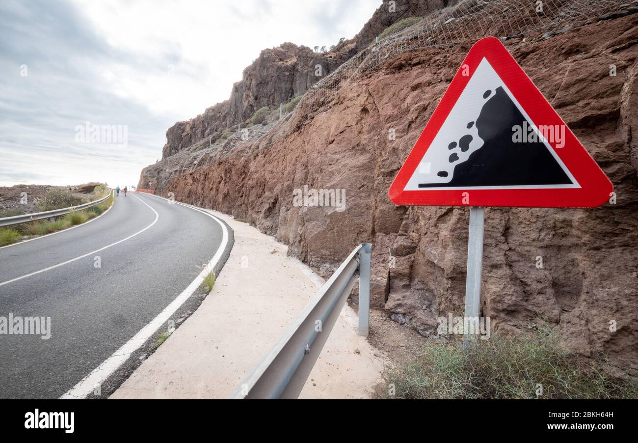 Warnschild für die Straßenverkehrssicherheit; Vorsicht vor fallenden Felsen. Ein rotes, dreieckiges Straßenschild, das vor möglichen Felsen und Trümmern in der Straße warnt. Stockfoto