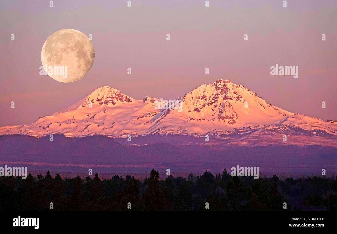 Eine Vollmond-Kulisse über den Three Sisters Peaks in den Oregon Cascade Mountains in der Nähe von Bend, Oregon. Stockfoto