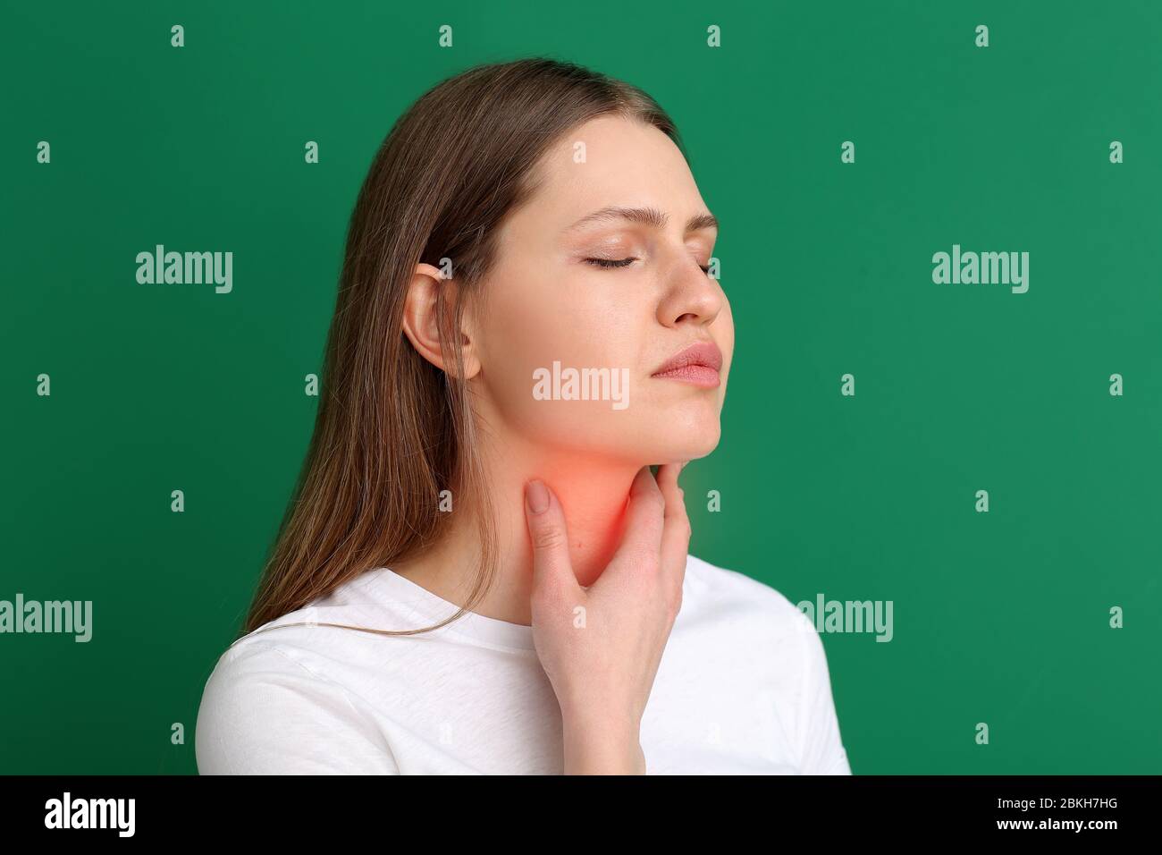 Junge Frau Überprüfung Schilddrüse auf farbigen Hintergrund Stockfoto