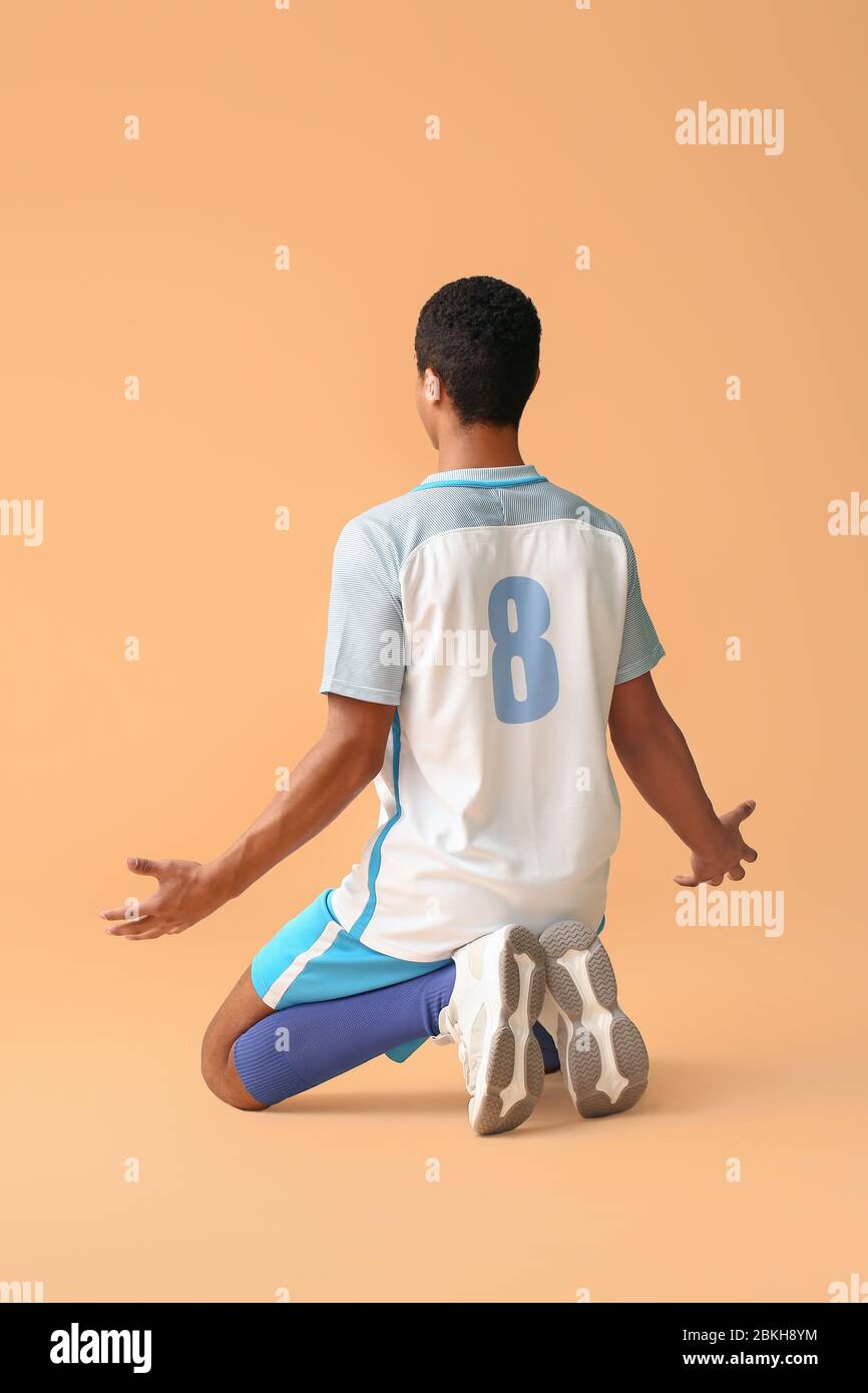 Happy African-American Football-Spieler auf farbigen Hintergrund Stockfoto