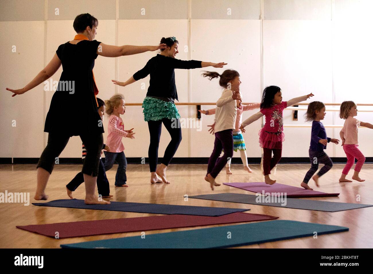 Kinder und Lehrer in Yoga-Bewegung Klasse, spielen folgen dem Führer Stockfoto