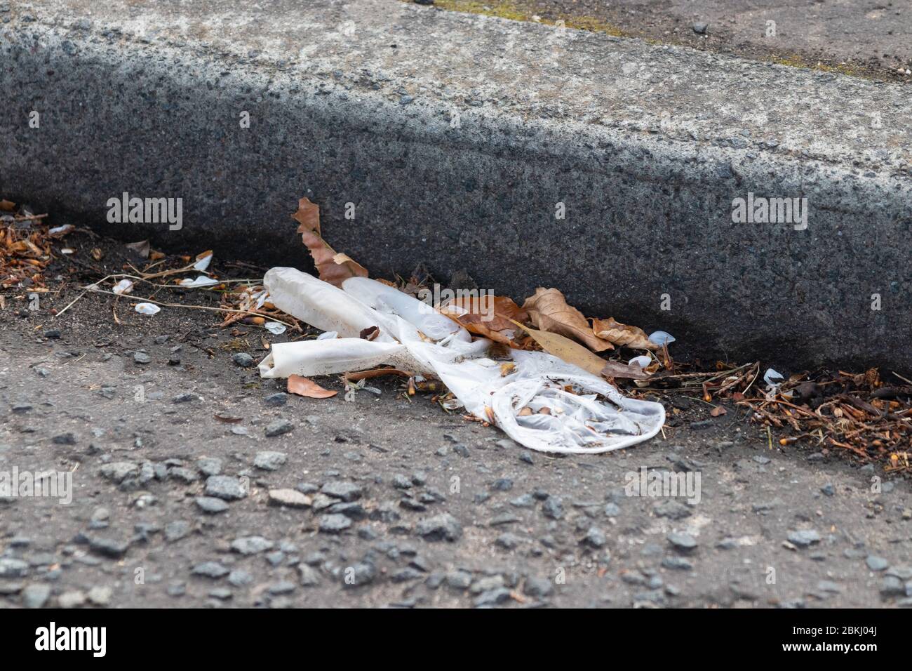 Ein ausrangter Latexhandschuh, der auf dem Boden liegt Stockfoto