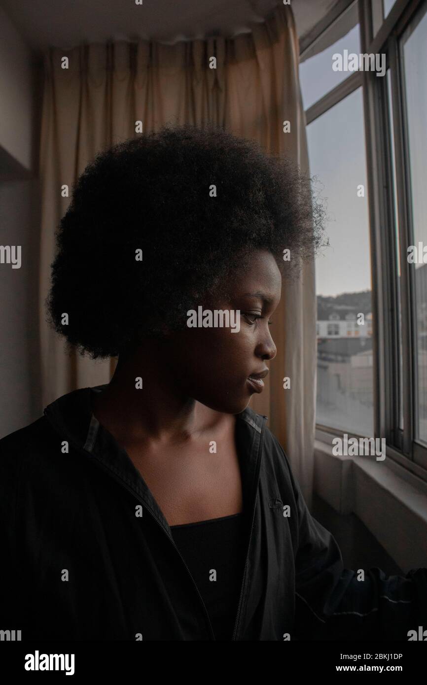Junge afrikanische Mädchen stehen am Fenster soziale Distanzierung Stockfoto