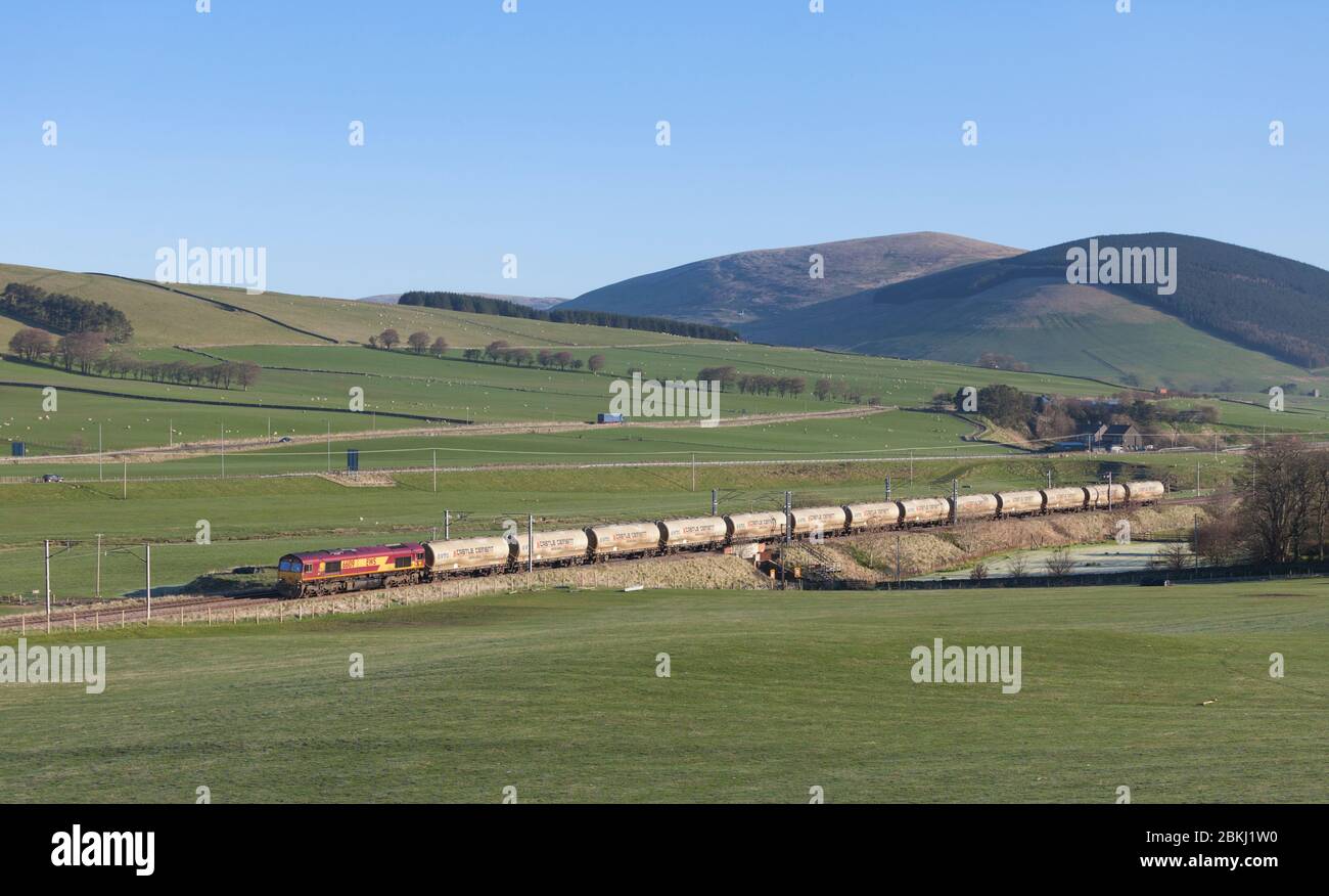 DB CARGO / EWS Lokomotive der Baureihe 66, die Wandell (nördlich von Abington, Südschottland) auf der Westküstenlinie mit einem Güterzug aus Zementtanks durchquert Stockfoto