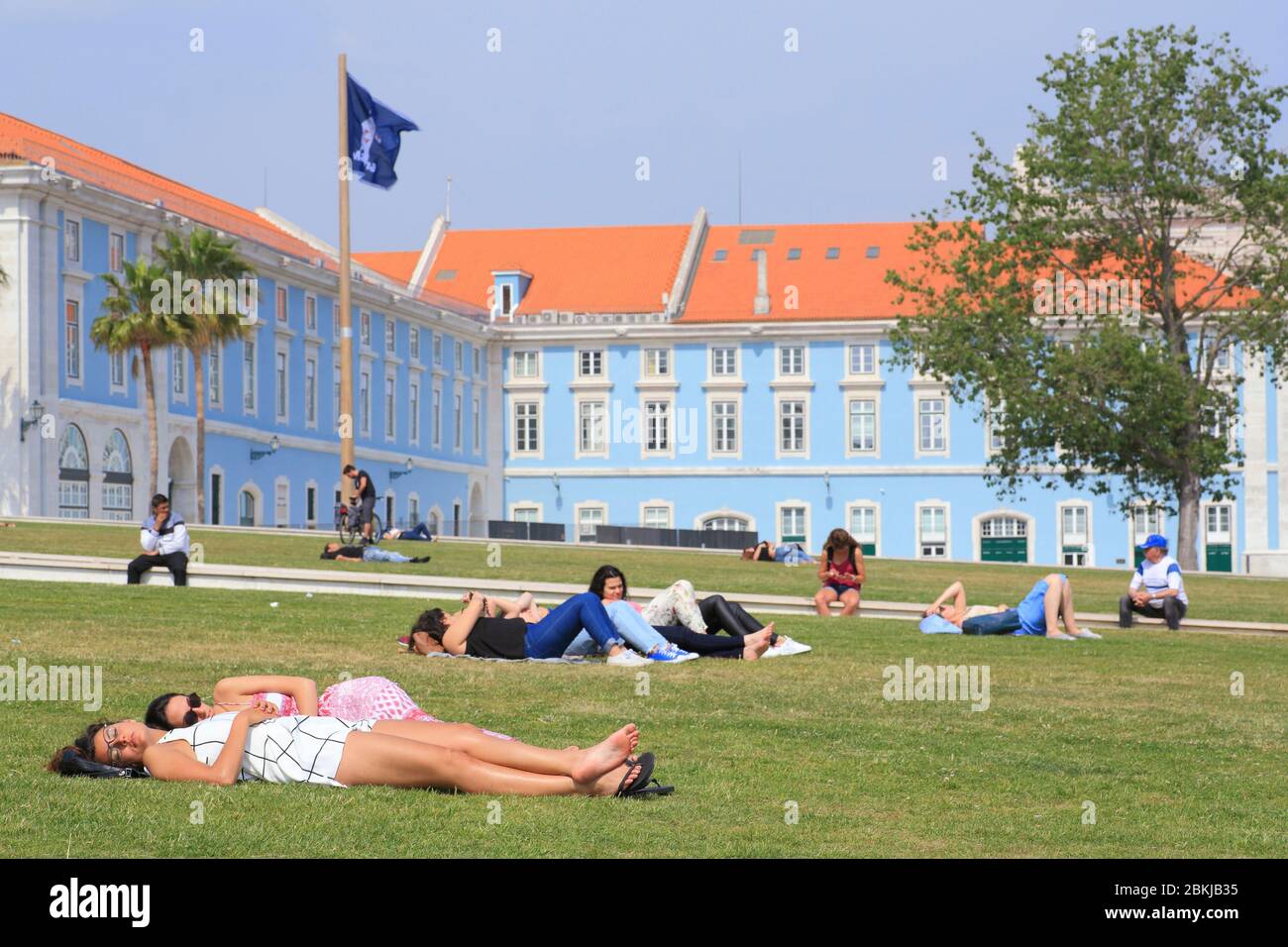 Portugal, Lissabon, Ribeira das Naus, Sonnenbaden auf der Wiese mit Regierungsgebäuden im Hintergrund Stockfoto