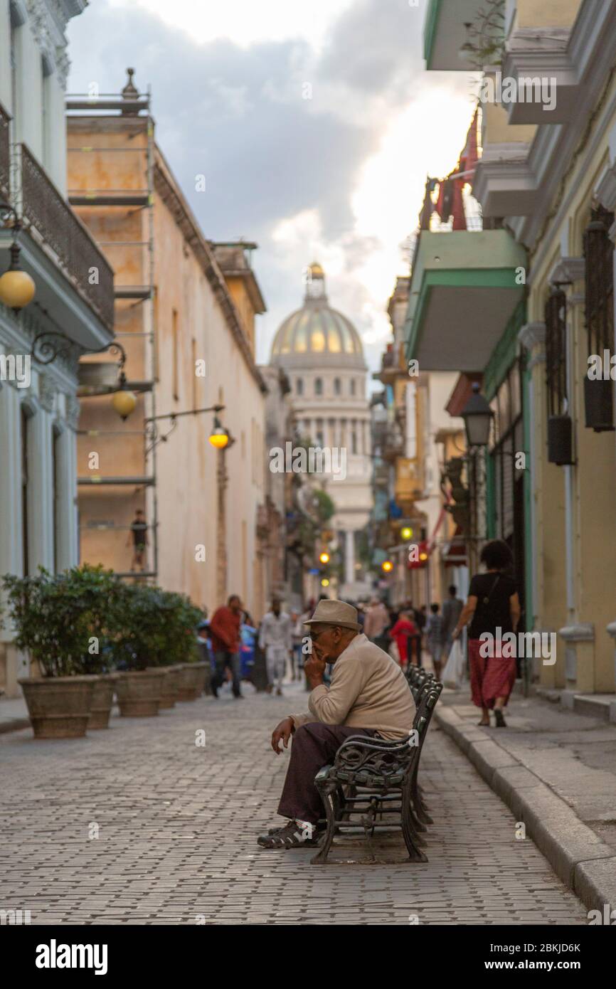Kuba, Havanna, Bezirk La Habana Vieja, Weltkulturerbe der UNESCO, kubaner rauchen eine Zigarre auf einer Bank, im Hintergrund das Kapitol Stockfoto