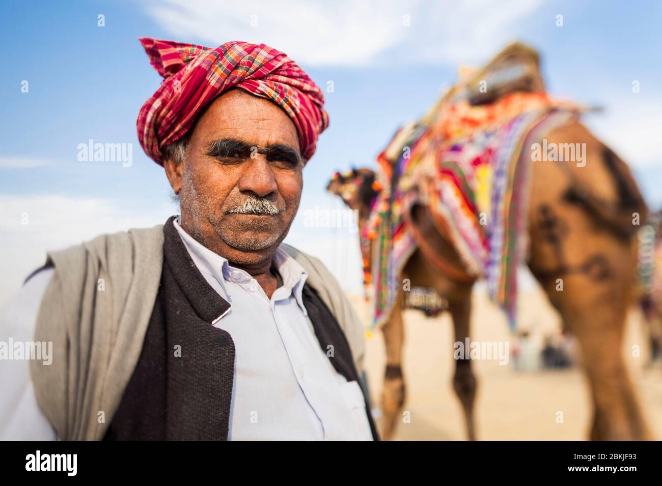 Indien, Rajasthan, Bikaner, Kamel-Festival, Porträt eines Mannes trägt einen Turban vor seinem dekorierten Kamel Stockfoto