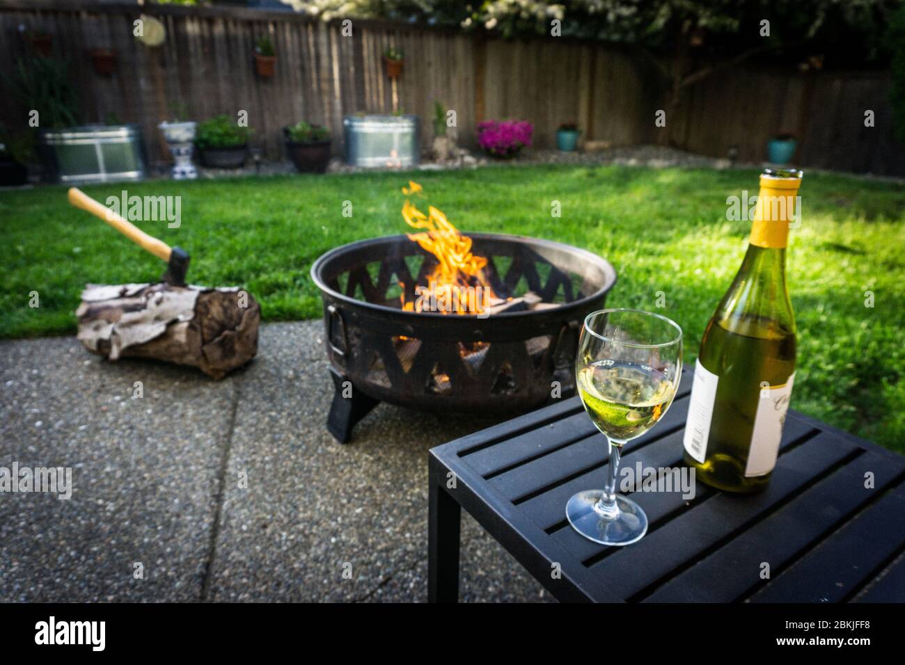 Ein Glas Weißwein, neben einer Flasche mit Feuer und im Hintergrund an einem schönen Frühlingstag geschlüpft. Stockfoto