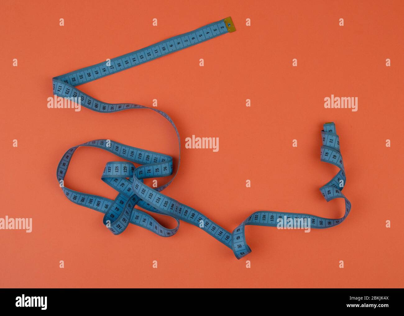 Blaues Maßband auf orangefarbenem Hintergrund mit Kopierfläche. Rahmen mit leerem Platz für Ihr Design. Stockfoto