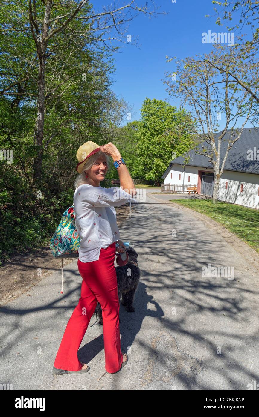 Europa, Luxemburg, Insenborn, attraktive ältere Frau, die ihren Hund spazieren geht, in der Nähe des Lac Sûre an einem Frühlingsmorgen Stockfoto