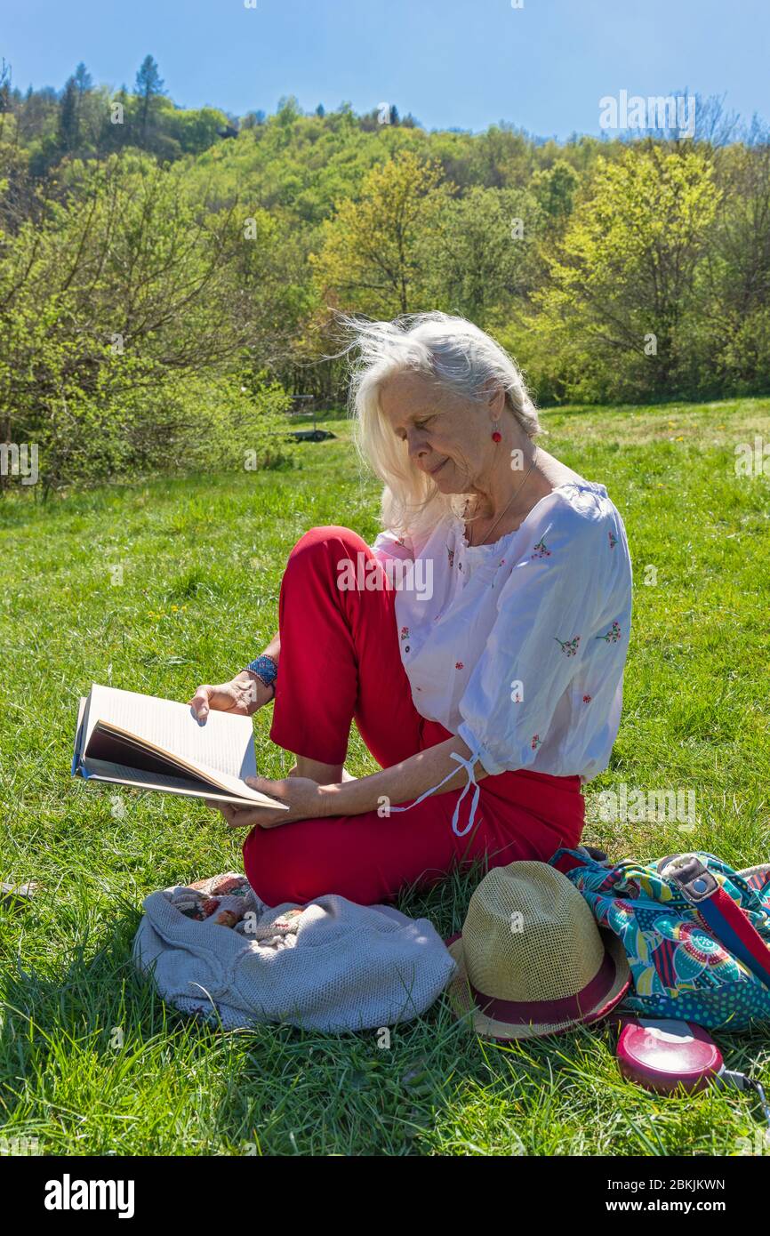 Europa, Luxemburg, Insenborn, attraktive ältere Frau, die während der Sperre von Covid-19 am verlassenen Lac Sûre liest Stockfoto