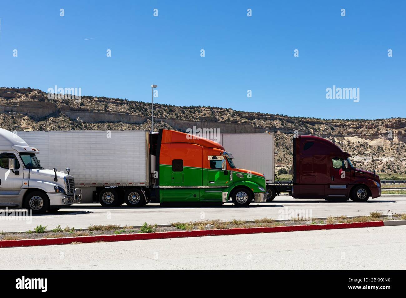 Moderne LKWs in verschiedenen Farben und Modellen Transport von verschiedenen Arten von Handelsgütern stehen in Reihe auf LKW-Stop-Parkplatz für LKW dri Stockfoto