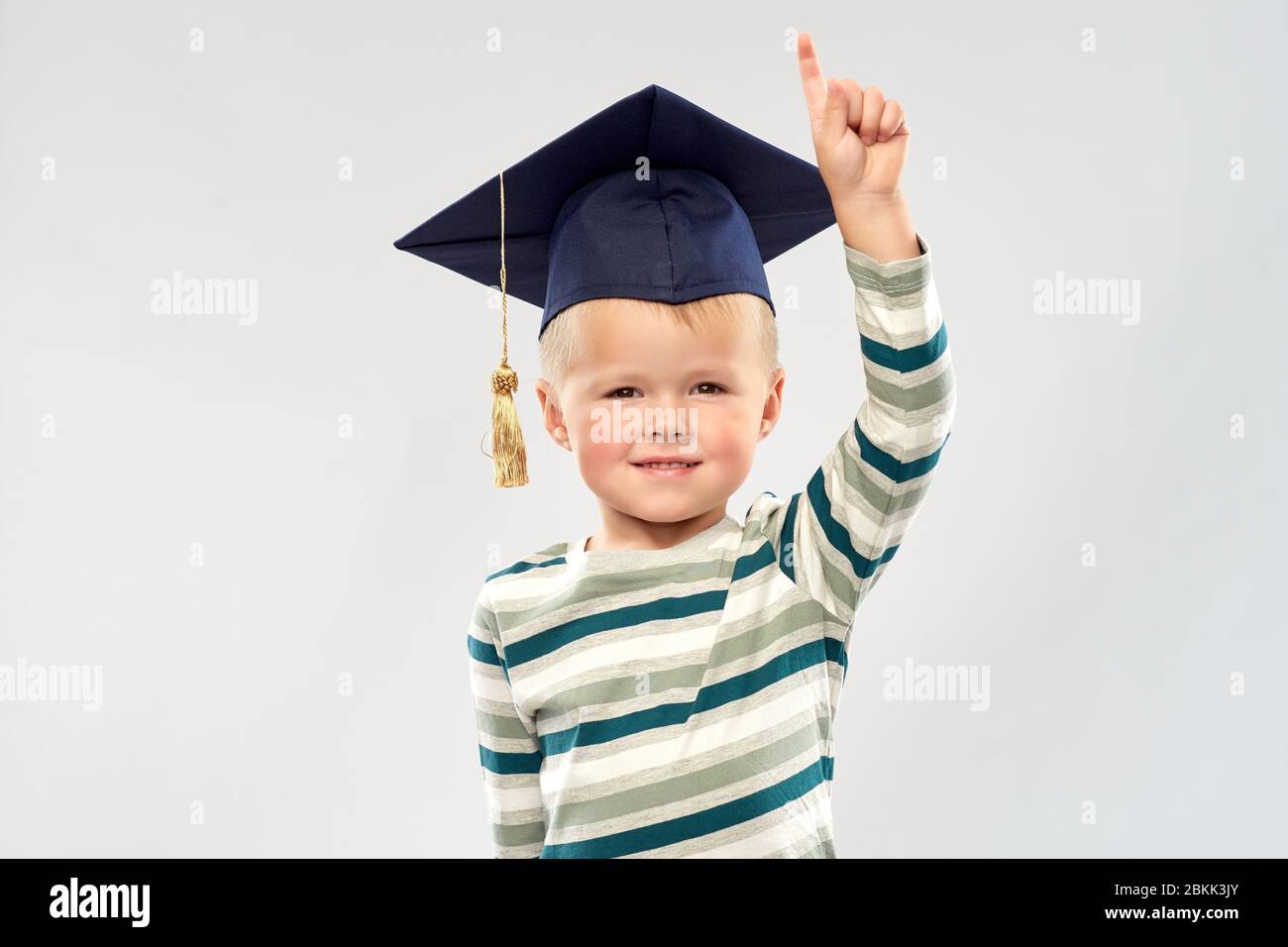 Kleiner Junge im Mörserbrett zeigt den Finger nach oben Stockfoto