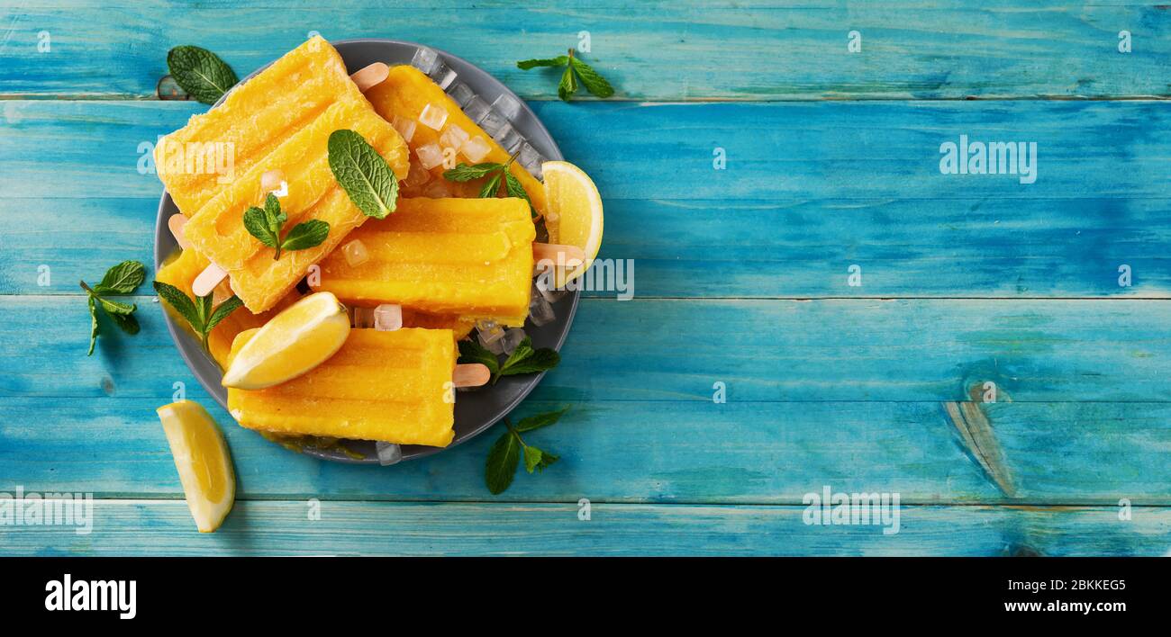 Draufsicht des veganen gelben Eissorbets auf blauem rustikalem Hintergrund Stockfoto