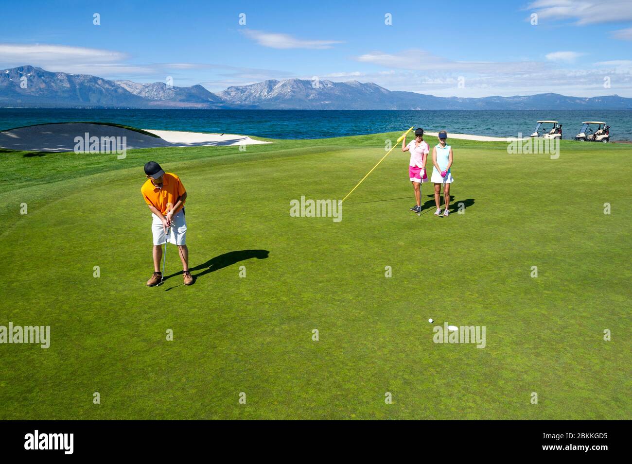 Ein Mann und zwei Frauen beenden eine Runde Golf in Edgewood Tahoe und setzen auf das 18. Loch mit Blick auf Mount Tallac im Hintergrund in Stateline, N Stockfoto