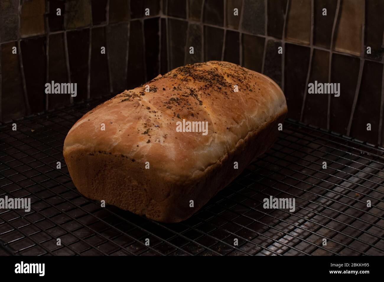 Ein Laib voll gekrächeltem Brot, perfekt gebacken und auf einem Drahtseil gekühlt. Moody und dunkle Farben Stockfoto