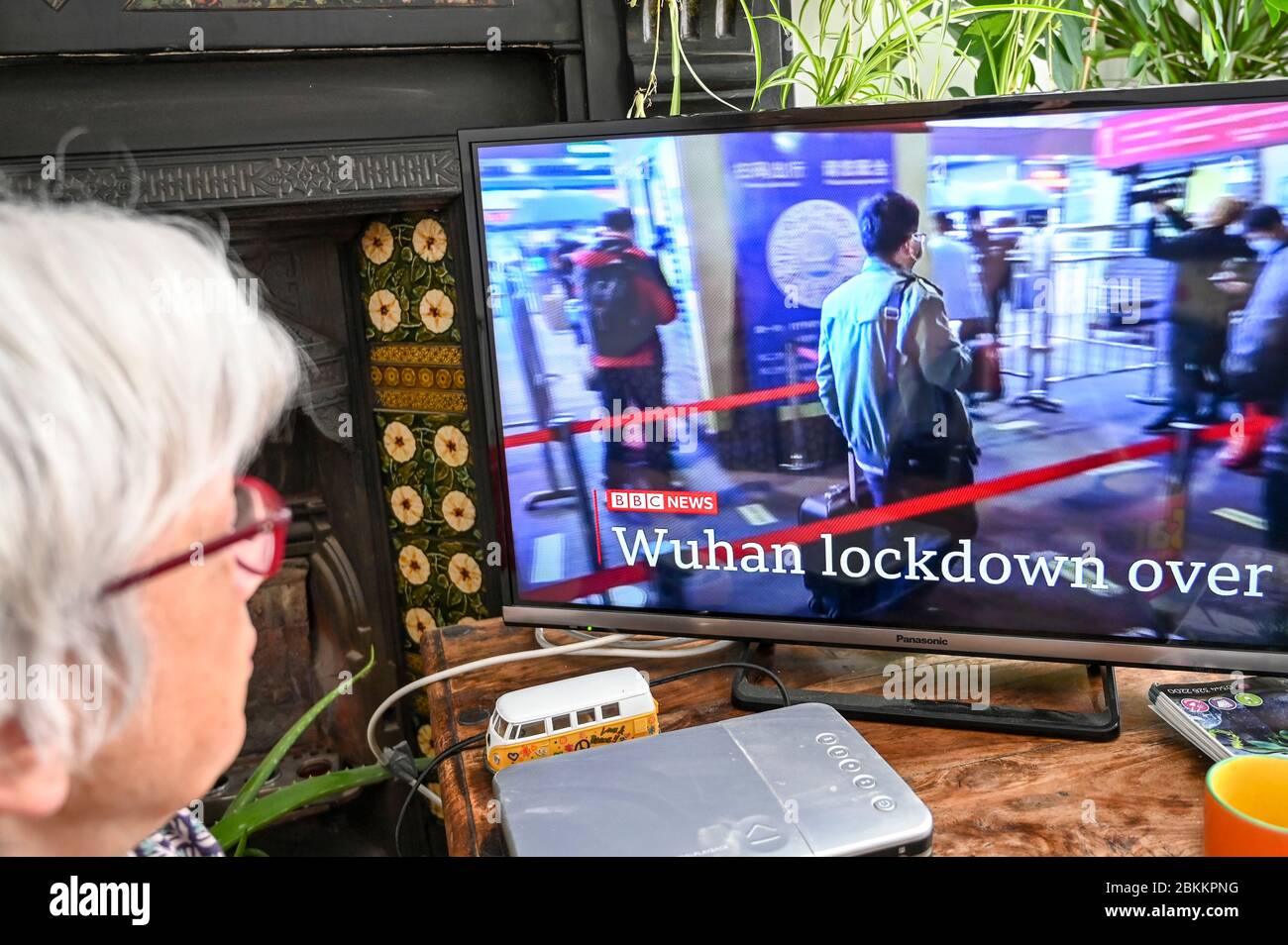 Eine Frau, die BBC Nachrichten mit Entwicklungen in Wuhan, China betreffend Covid-19 mit der Überschrift 'Wuhan Lockdown over' beobachtet. Stockfoto