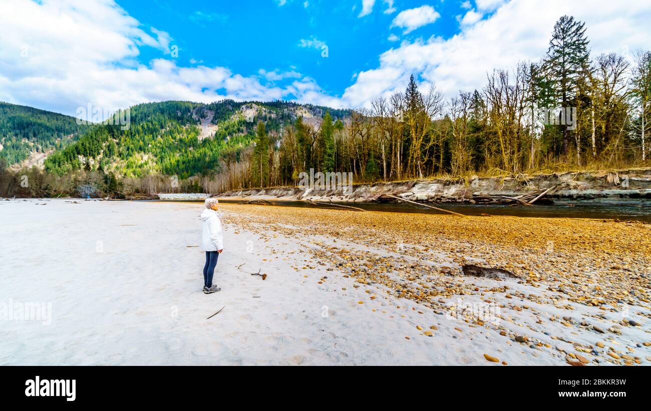 Ältere Frau auf einer Wanderung entlang der Eisenoxid gefärbten Felsen entlang der Küste bei niedrigem Wasser im Squamish River im Upper Squamish Valley, BC, Kanada Stockfoto