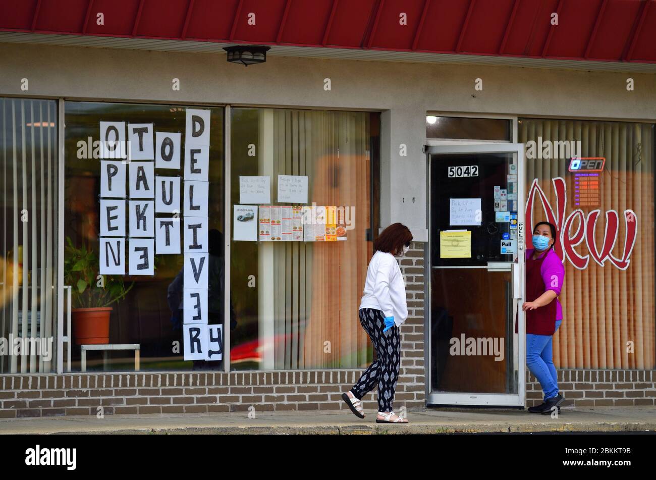 Hanover Park, Illinois, USA. Als asiatisches Restaurant in einem Vorort von Chicago tragen weibliche Mitarbeiter Schutzkleidung, während sie die Bestellungen der Kunden abholen. Stockfoto