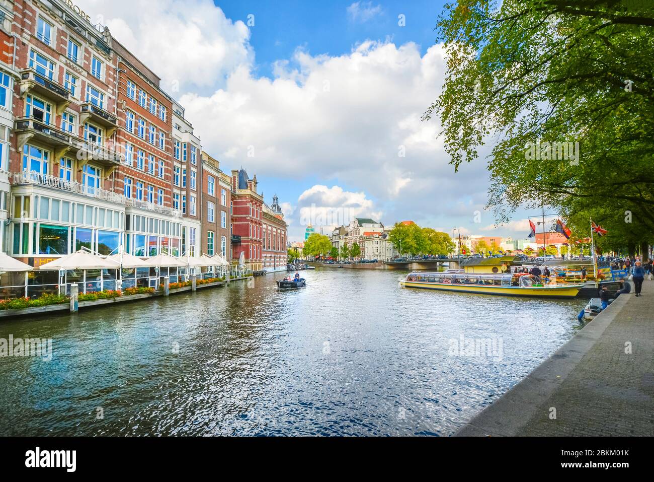 Ein kleines Boot gleitet vergangenen touristischen Boote auf einem großen Kanal in der Nähe des Museumsviertels von Amsterdam im frühen Herbst. Stockfoto