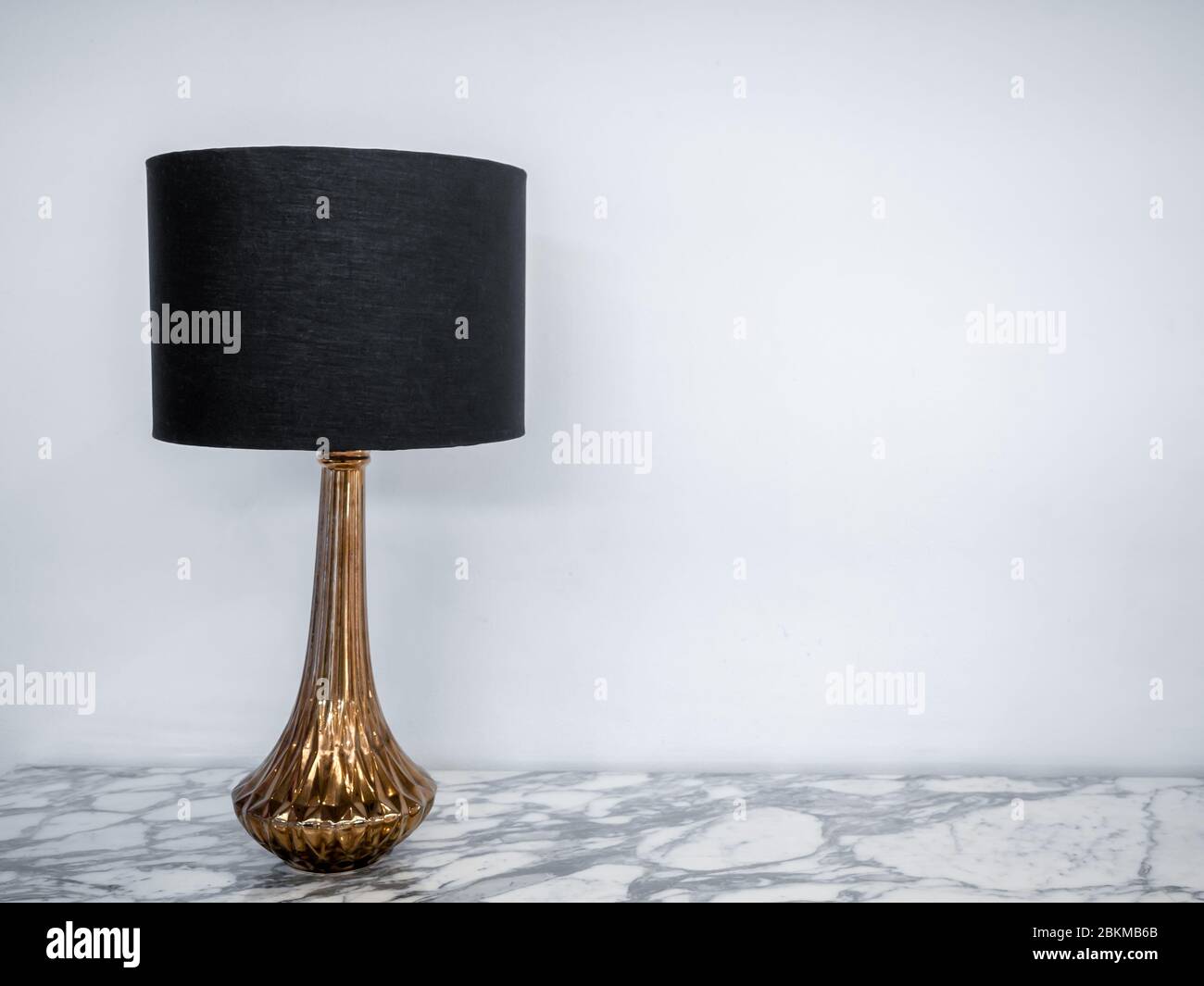 Vintage Tischlampe auf Marmortisch. Luxus-Lampe mit schwarzem Stoff und Gold auf weißem Hintergrund mit Kopierraum entworfen. Stockfoto