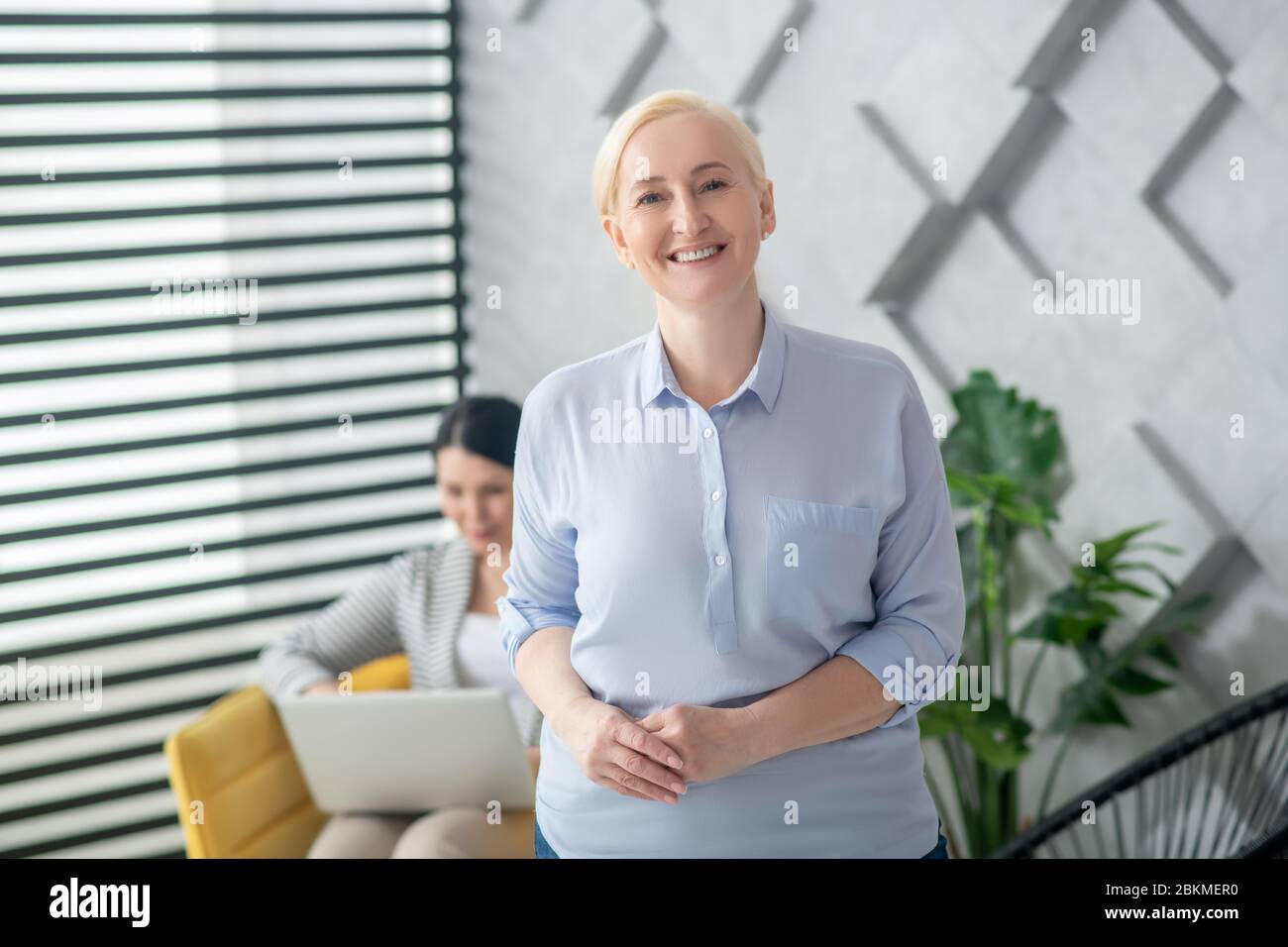 Erwachsene lächelnde blonde Frau im Zimmer stehen. Stockfoto