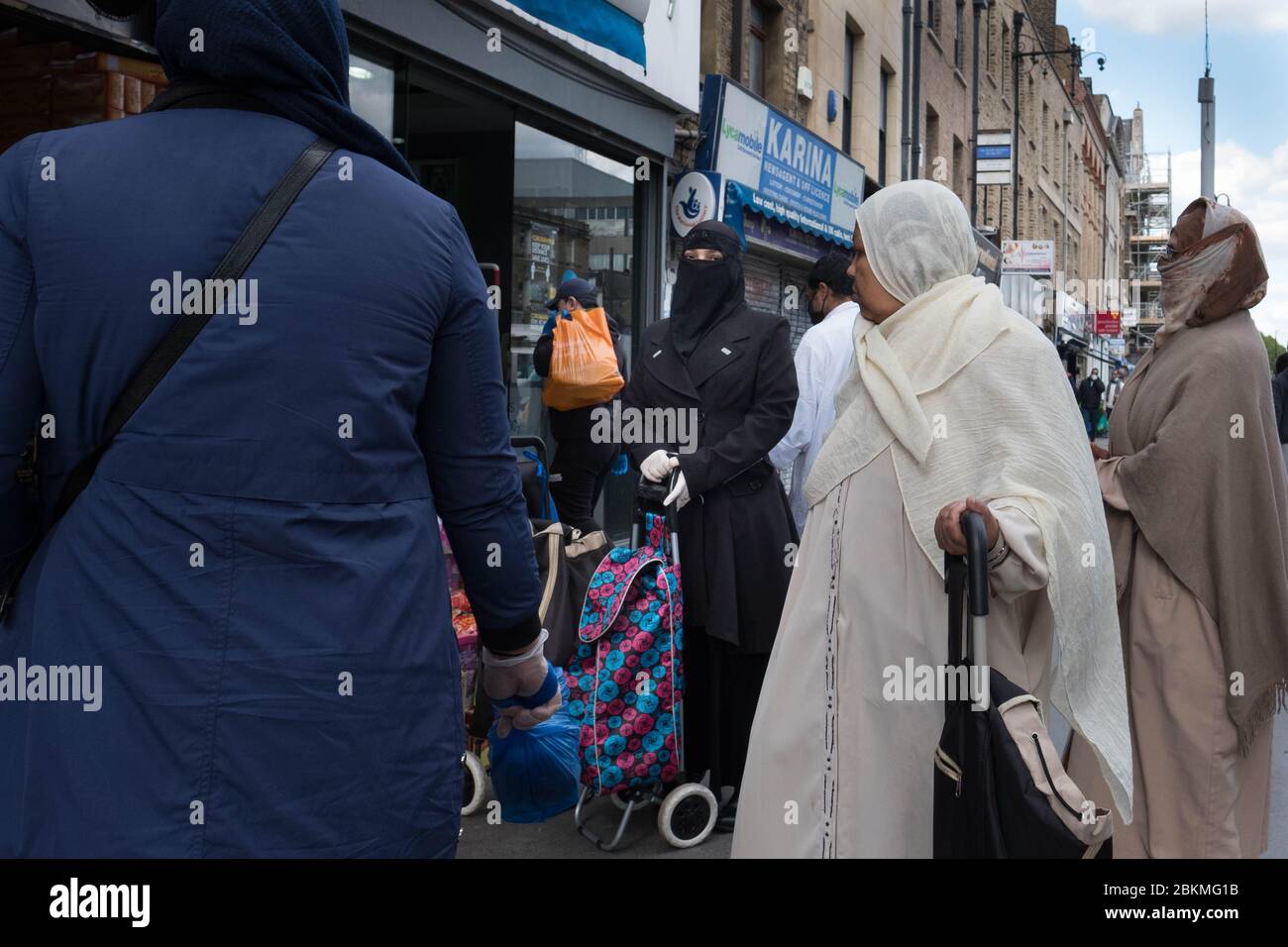 Mitglieder der islamischen Gemeinschaft in Whitechapel im Osten Londons machen während des heiligen Monats Ramadan ihre täglichen Geschäfte, während Großbritannien weiterhin in der Lockdown-Zeit arbeitet, um die Ausbreitung des Coronavirus einzudämmen. Stockfoto