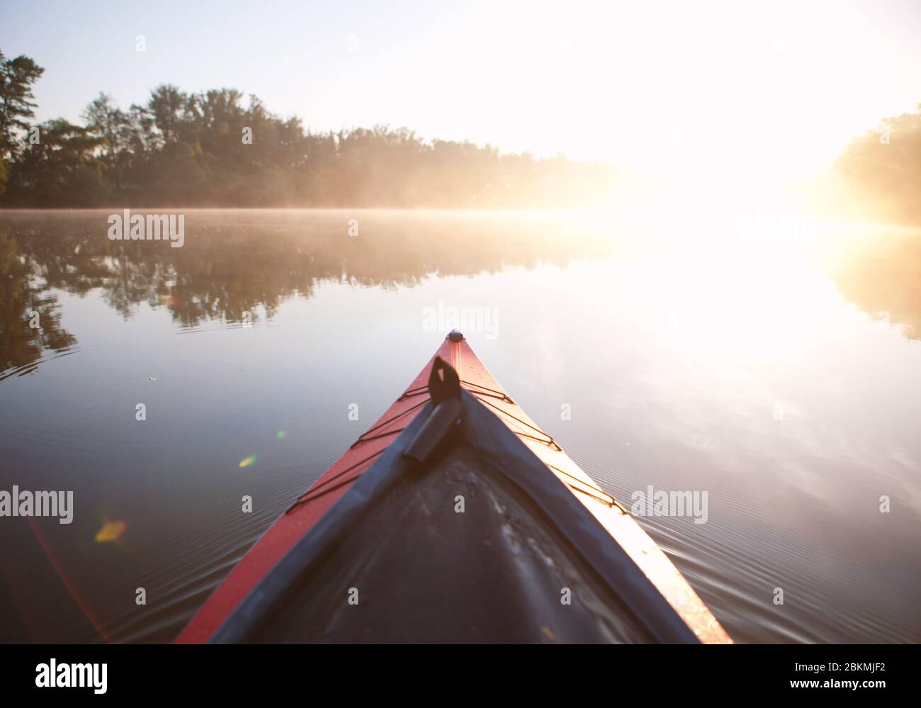 Paddelkajak auf dem nebligen Fluss bei Sonnenaufgang Stockfoto