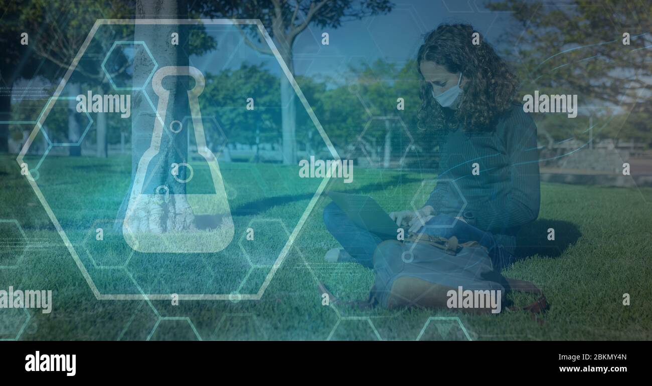 Digitale Illustration einer Frau mit Gesichtsmaske, die auf Gras in einem Park über einem Reagenzglas-Symbol sitzt Stockfoto