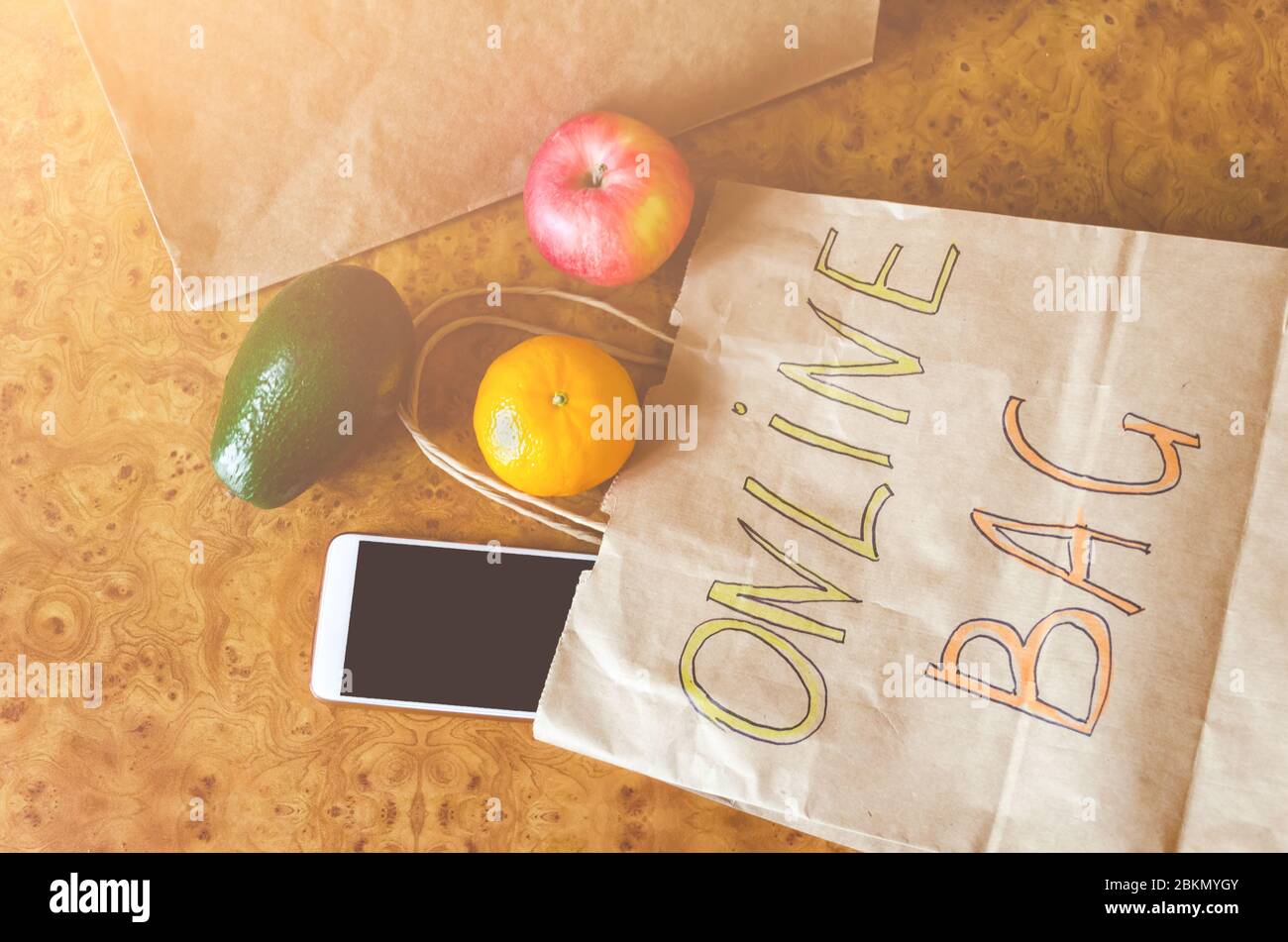 Papiertüte mit Aufschrift - Online-Tasche, verschiedene frische Früchte, Gemüse auf Holzhintergrund. Online-Shopping und kontaktloses Lieferkonzept. Bis Stockfoto