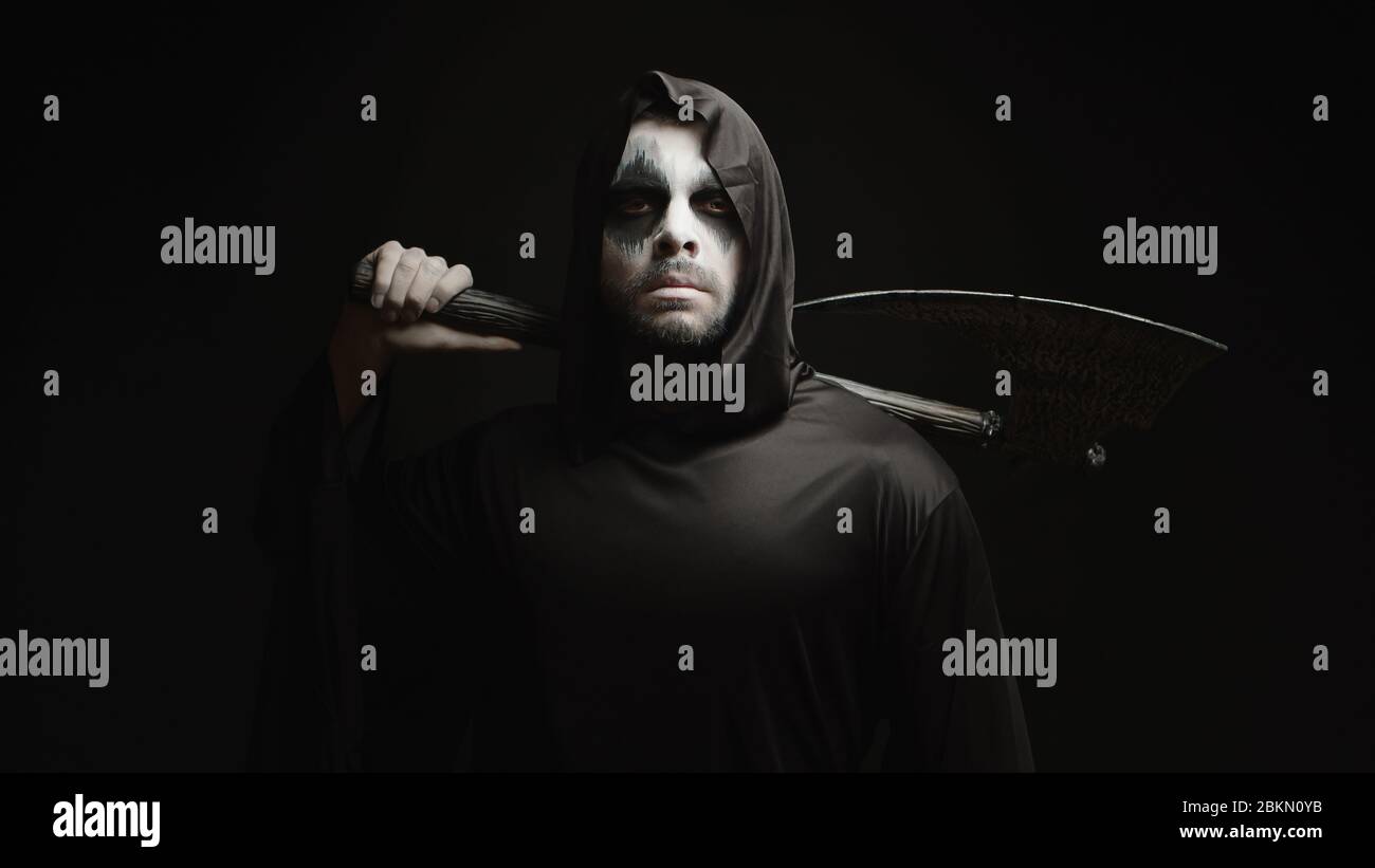 Grim Reaper über schwarzem Hintergrund mit Axt in den Händen. Halloween Kostüm. Stockfoto