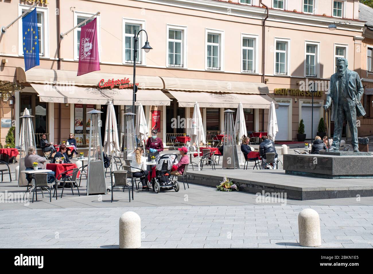 Bar und Restaurant im Freien mit Kunden und Kellnerin mit Maske und Handschuh in Vilnius, der litauischen Hauptstadt, die sich wieder in eine riesige Open-Air-Cafestadt öffnet Stockfoto