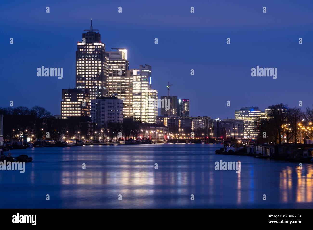 Moderne Bürotürme im Morgengrauen im Amsterdamer Geschäftsviertel Amstel in der größten Stadt der Niederlande. Aufnahme als lange Belichtung, um die Wasserbewegung zu glätten Stockfoto