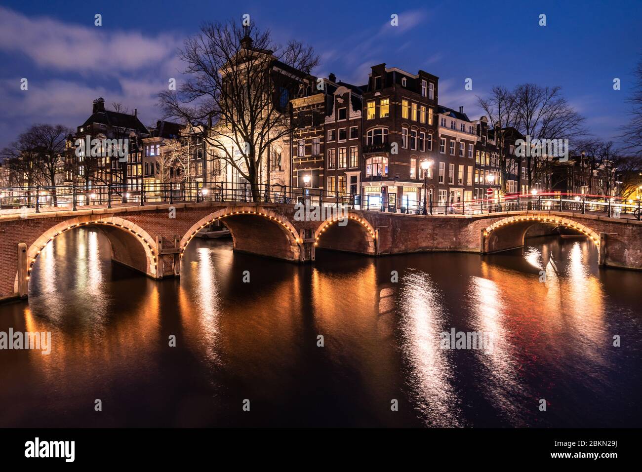 Stimmungsvolle Aussicht auf die berühmten Amsterdamer Kanäle und traditionellen holländischen Häuser in der größten Stadt der Niederlande bei Nacht. Aufnahme als Langbelichtung t Stockfoto