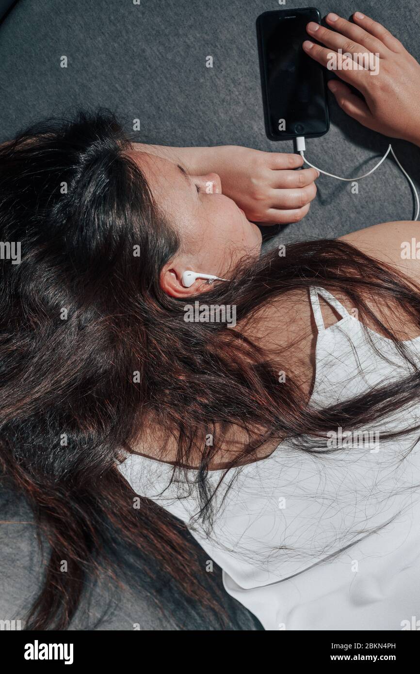 Junge Frau schlief mit Smartphone im Bett, während sie einen Film, ungesund Einschlafen Stockfoto