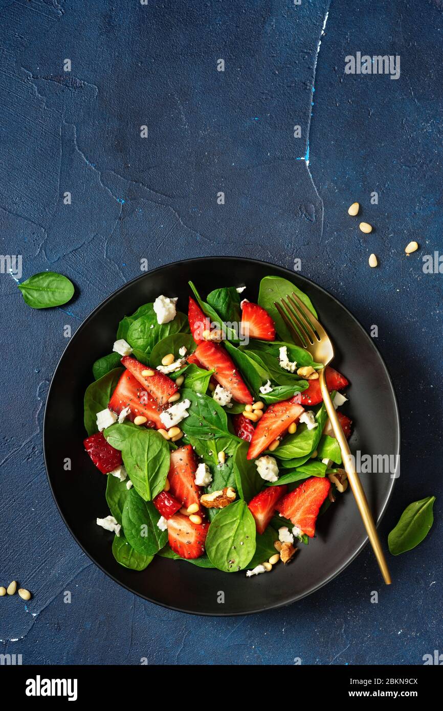 Vertikale Aufnahme von farbenfrohen frischen Salaten mit Erdbeeren, Spinat und Feta Stockfoto