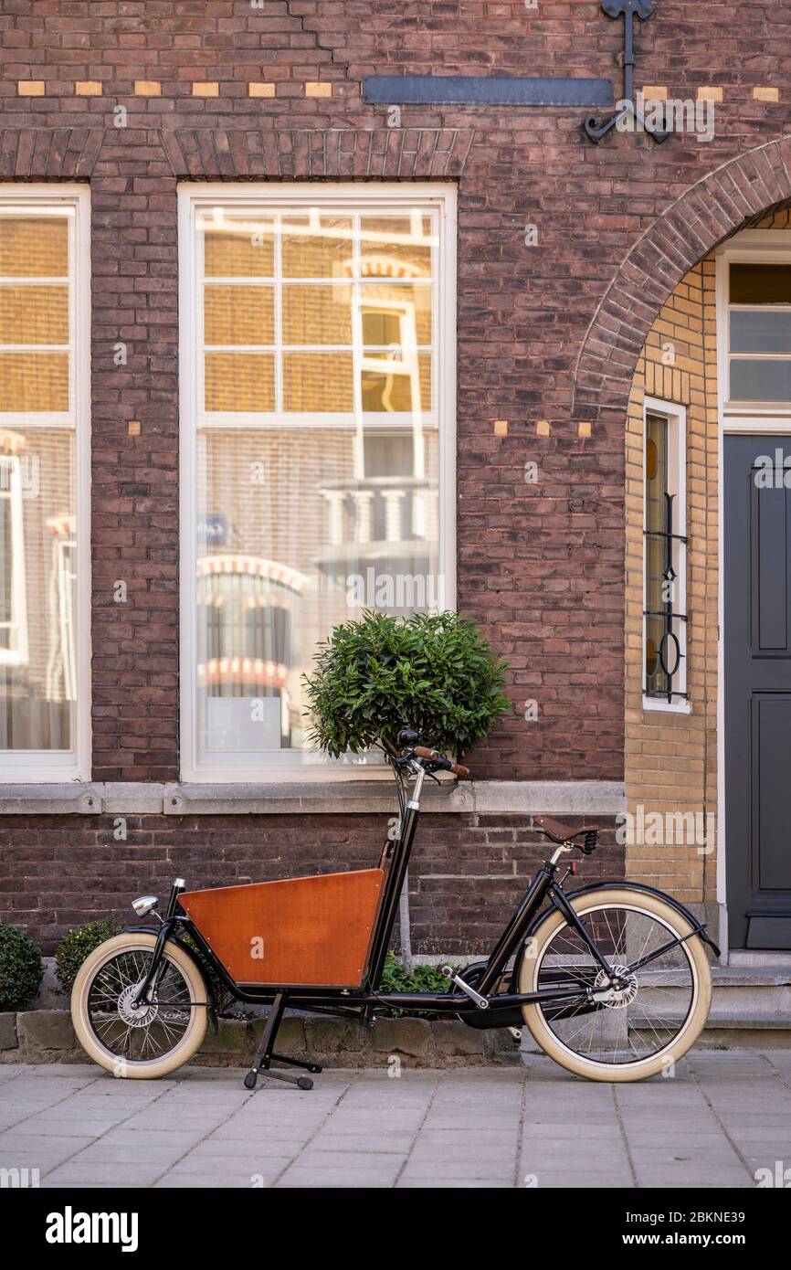 Typisch holländisches Fahrrad vor einem Haus geparkt. Moderne städtische Eltern nutzen diese Trägerräder, um ihre Lebensmittel oder Kinder zu transportieren Stockfoto