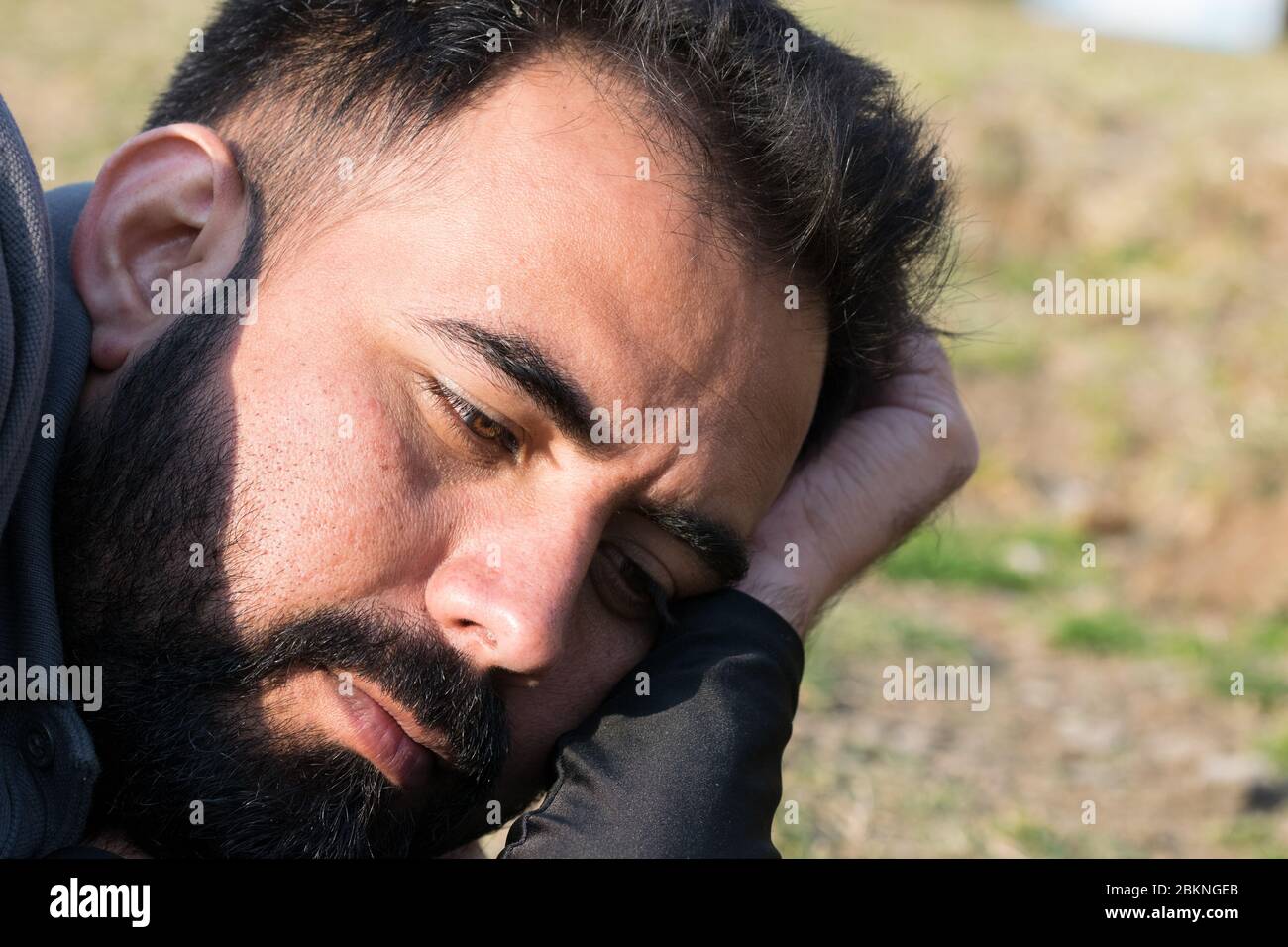 Ehrliche Nahaufnahme eines bärtigen jungen Mannes, der wegschaut Stockfoto
