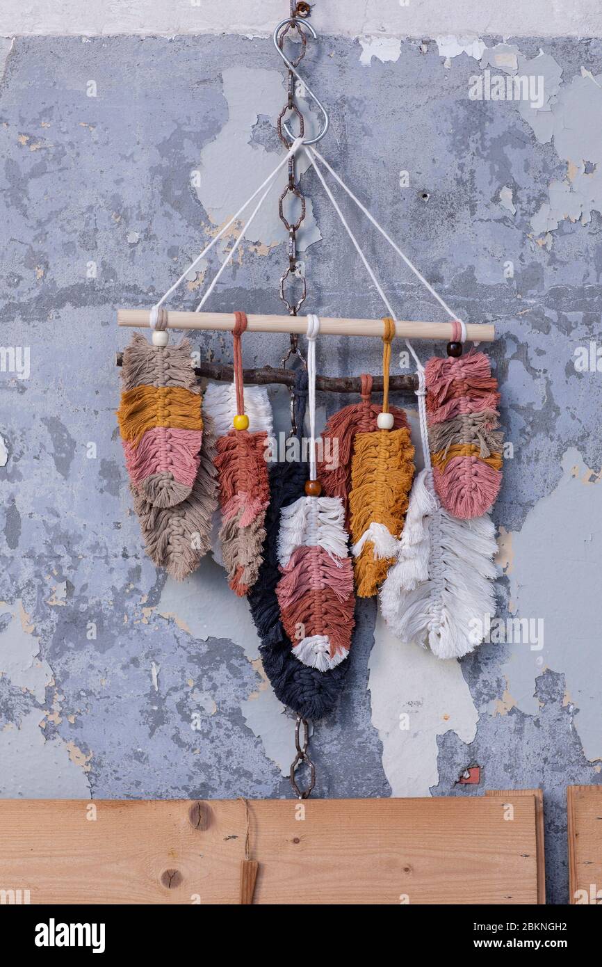 Ein trendiger macrame handgemachte Wand hängen aus bunten Baumwollfedern hängen an einer rustikalen Betonwand in einem Loft-Interieur. Öko-Handstück im Hippie-Stil Stockfoto