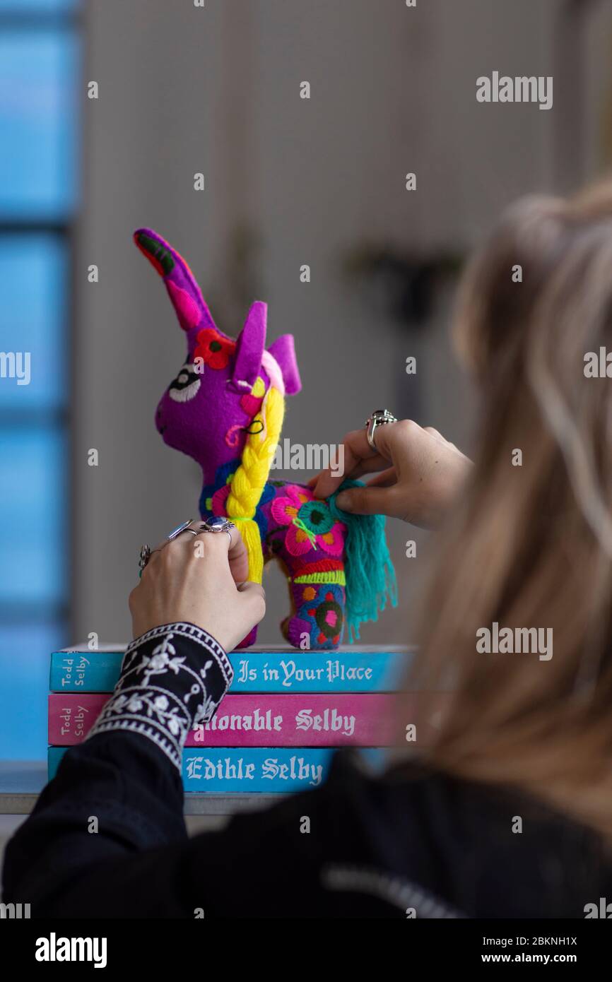 Eindhoven, Niederlande, 2. Februar 2020. Eine Frau mit vielen Ringen, die ein traditionelles handgemachtes buntes mexikanisches Einhorn auf einem Haufen Fash platziert Stockfoto