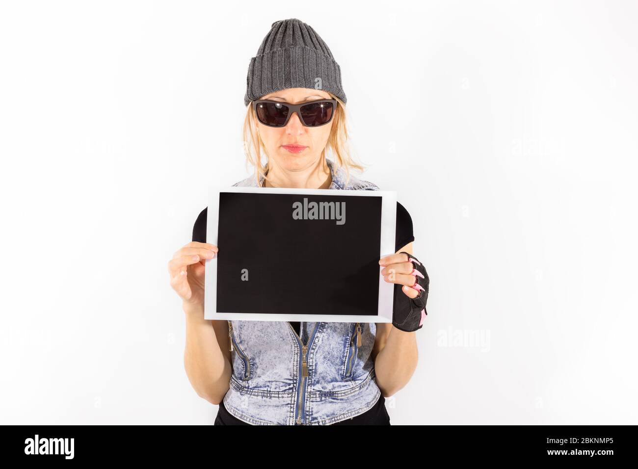 Harte Frau mit einem Schild und Kopierer Raum, isoliert auf weiß. Mädchen Werbung für Ihr Produkt auf einem leeren schwarzen Schild. Mädchen zeigt ein leeres Brett Stockfoto