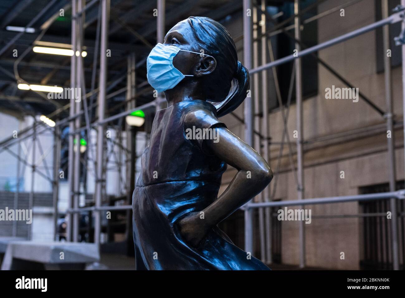 Die Statue "Fearless Girl" von Kristen Visbal vor der New Yorker Börse, die während der COVID-19-Pandemie eine chirurgische Gesichtsmaske trägt. Stockfoto