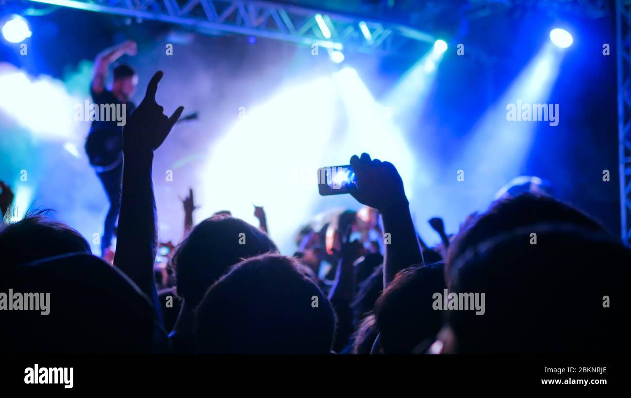 Unerkennbare Hände Silhouette Aufnahme Foto oder Videoaufnahme von Live-Musik Konzert mit Smartphone. Leute feiern vor der Bühne Stockfoto