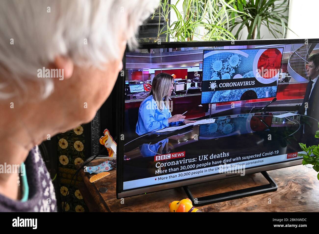 Coronavirus-Grafik in Fernsehnachrichten mit der Überschrift "Coronavirus UK Todes more than 30,000". Von einem älteren Zuschauer beobachtet. Stockfoto