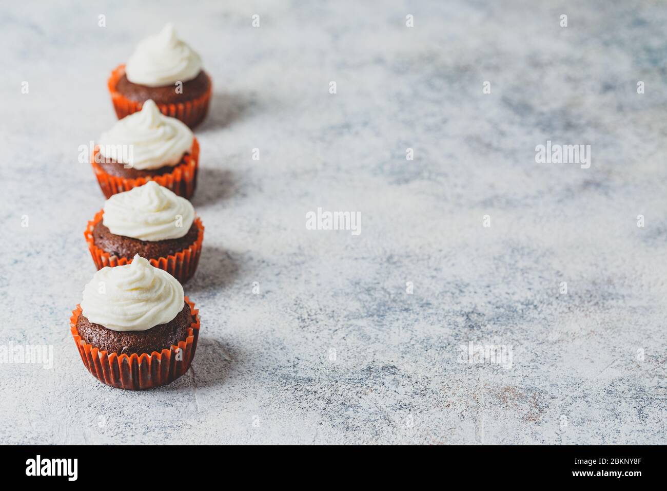 Schokoladenkuchen mit Käsekappe in orangefarbenen Papierzinnen auf hellem Hintergrund Stockfoto