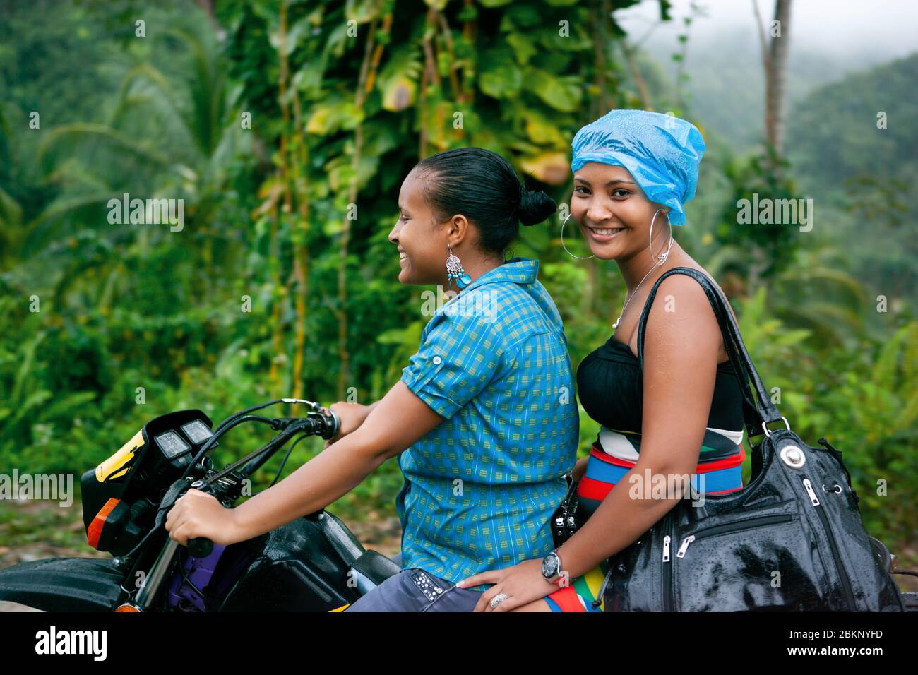 Dominikanische Leute. Zwei Mädchen auf einem Motorrad, vor der Kulisse der Natur der Samana Halbinsel. Dominikanische Republik. 26.01.2013 Stockfoto