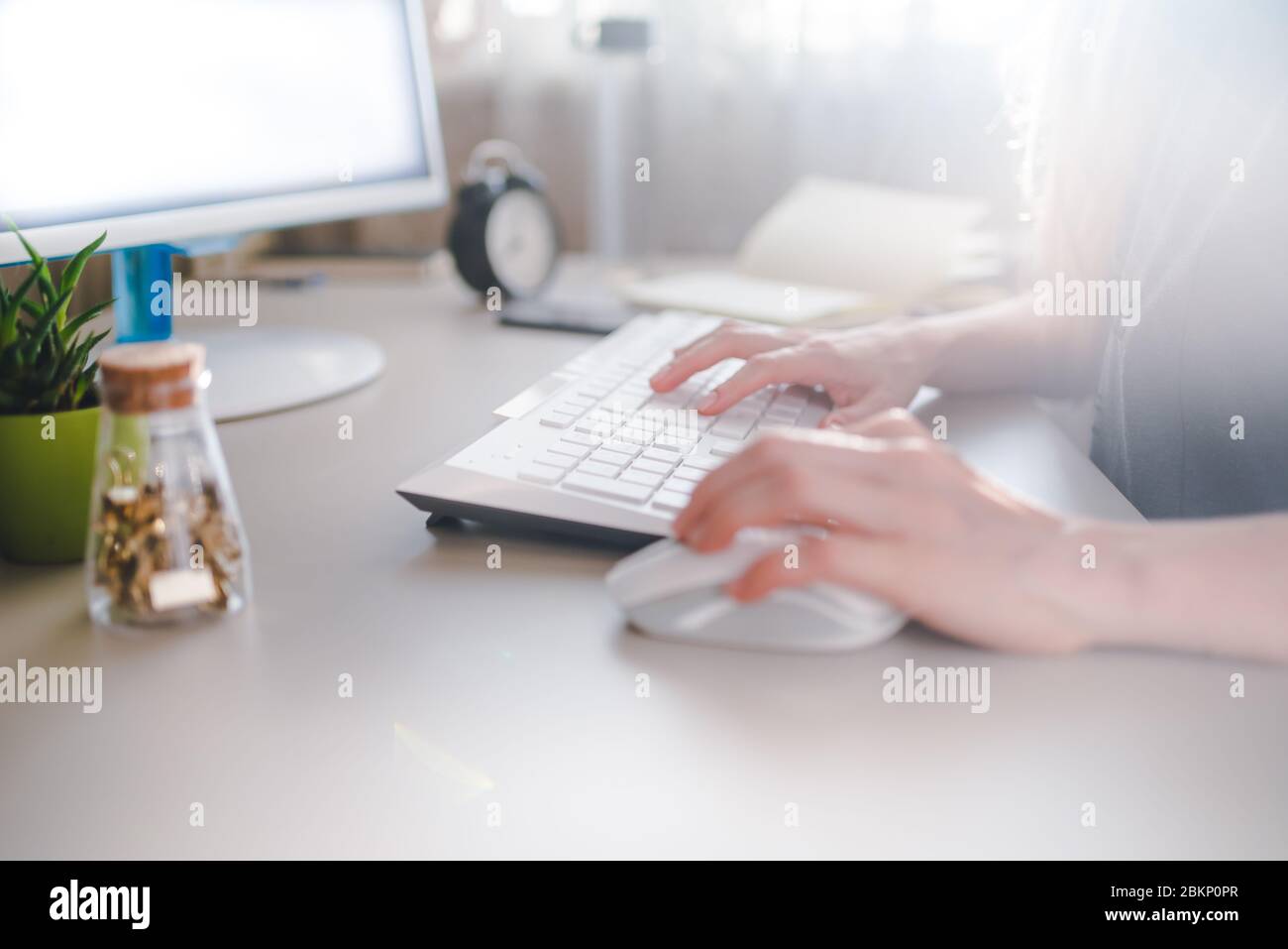 Mädchen tippt auf einer weißen Tastatur und verwendet Maus Stockfoto